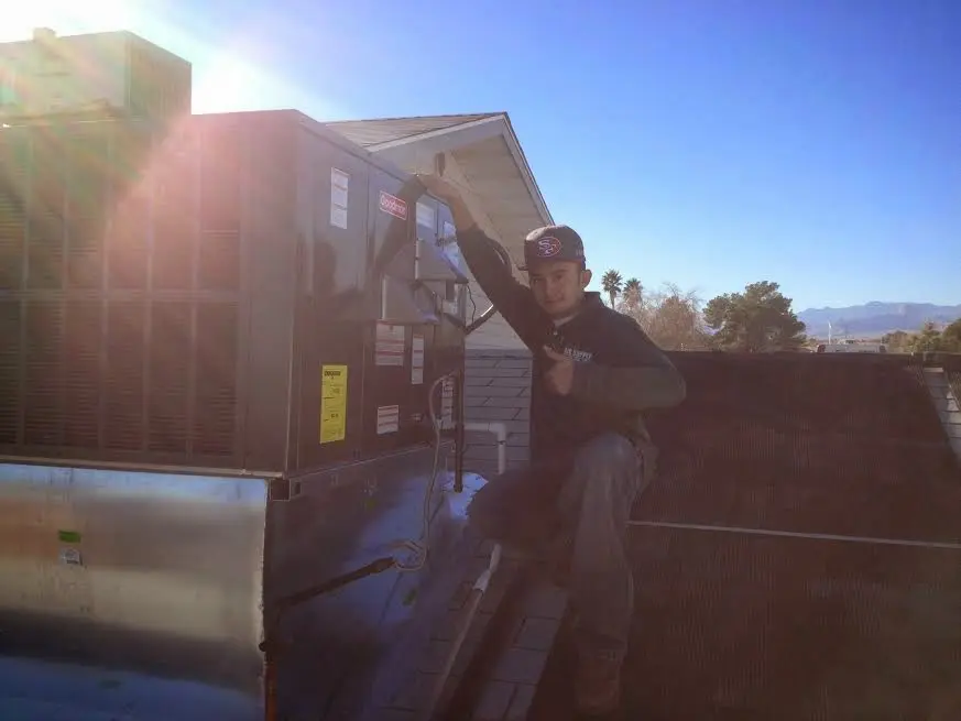 HVAC technician performing Air Duct Cleaning on a rooftop unit in Plainview